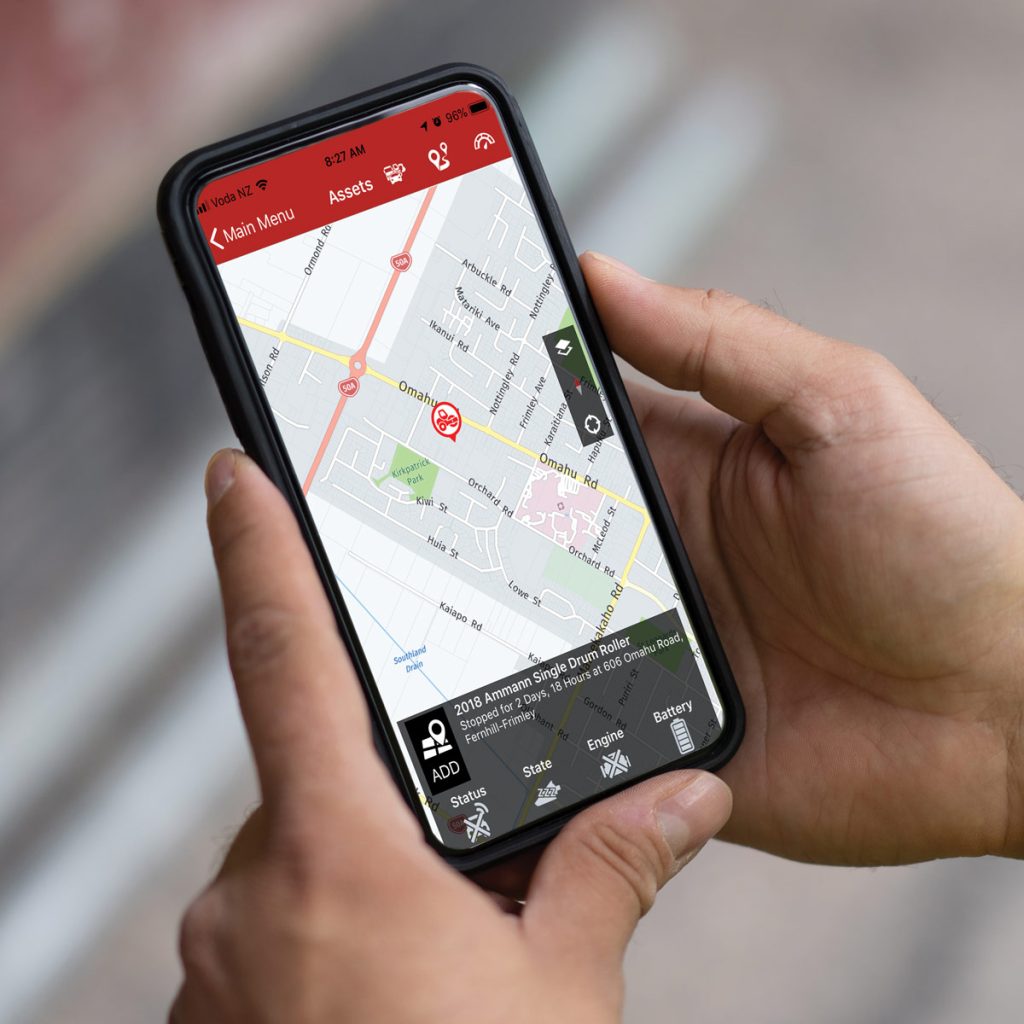 Photo of someone holding a smartphone running the YR Connect app, which shows a map showing the physical location of an Ammann Single Drum Roller